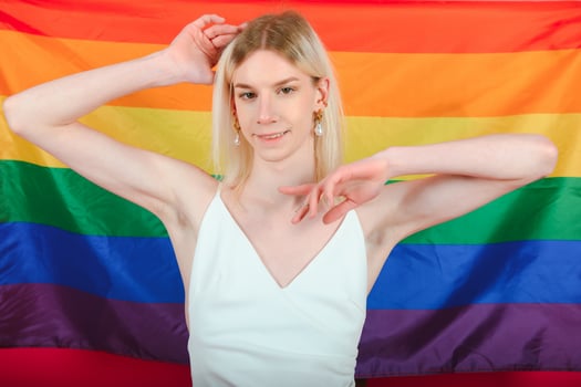 Young gay man 20s with make up wrapped in rainbow striped flag isolated on background, studio portrait. People lifestyle fashion lgbtq concept. photo