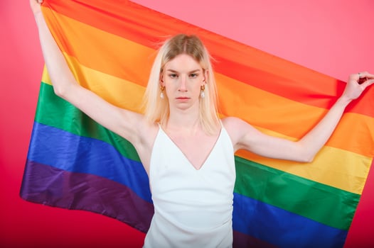 Young gay man 20s with make up wrapped in rainbow striped flag isolated on background, studio portrait. People lifestyle fashion lgbtq concept. photo