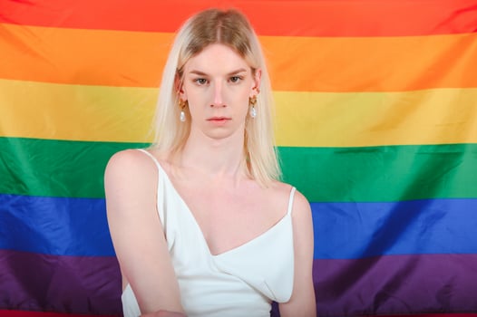 Young gay man 20s with make up wrapped in rainbow striped flag isolated on background, studio portrait. People lifestyle fashion lgbtq concept. photo