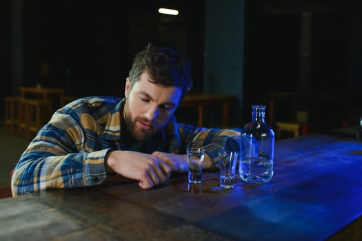 It was a hard day. Depressed young man drinking vodka in bar photo