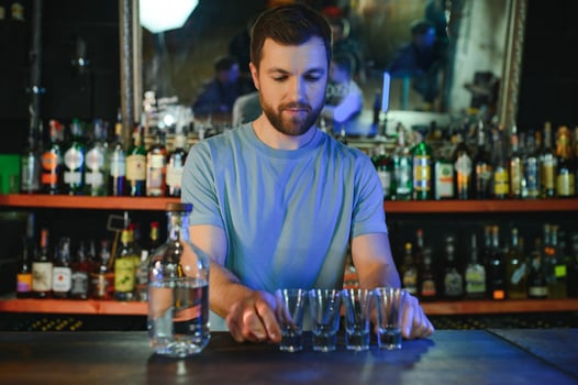 Barman pouring hard spirit into glasses in detail photo