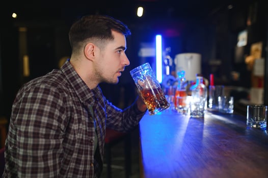 Handsome bearded man drinking beer at the bar counter in pub photo