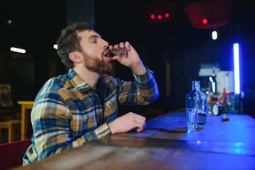 It was a hard day. Depressed young man drinking vodka in bar photo