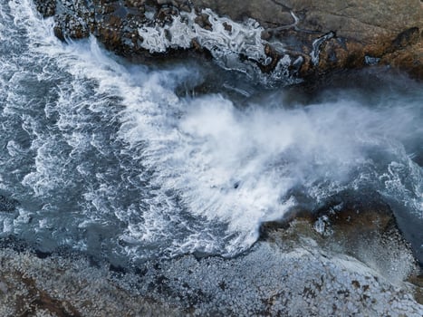 Aerial View of Powerful Waterfall Cascading Over Rugged Rocks in Iceland photo