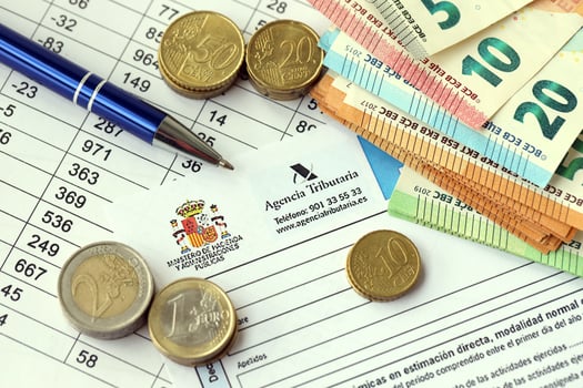 KYIV, UKRAINE - APRIL 20, 2024 Agencia Tributaria logo from blank tax form and many euro banknotes on office table photo