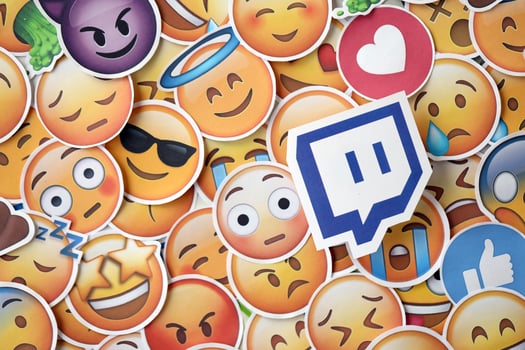 KYIV, UKRAINE - APRIL 20, 2024 Twitch logo and large set of stickers with Emoji yellow faces. Emoji is a pictogram or smiley embedded in text and used in electronic messages photo