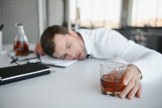 Alcoholism at work. Tired employee drinking alcohol at workplace, can not handle stress. photo