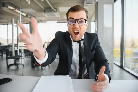 Angry senior businessman sitting at his desk and screaming photo