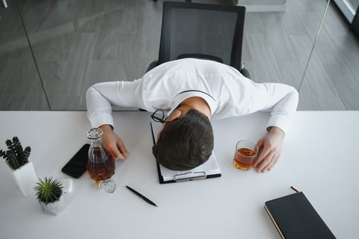 Alcoholism at work. Tired employee drinking alcohol at workplace, can not handle stress. photo