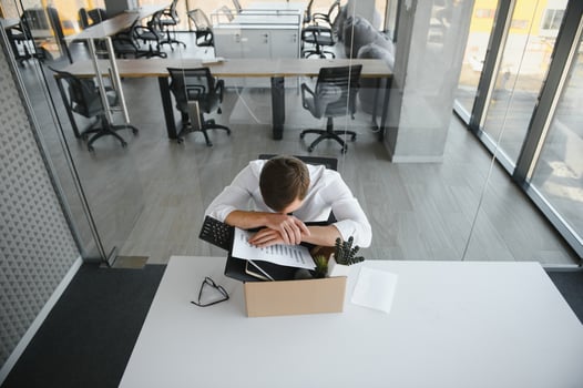 Sad Fired. Let Go Office Worker Packs His Belongings into Cardboard Box and Leaves Office. Workforce Reduction, Downsizing, Reorganization, Restructuring, Outsourcing. Mass Unemployment Market Crisis photo