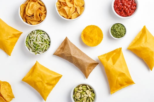 Flat lay of various snacks in bowls and paper bags photo