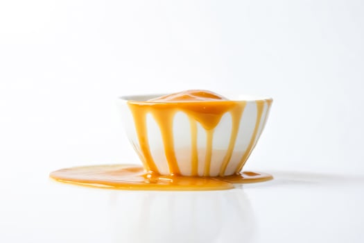 Dripping caramel sauce in a white bowl photo