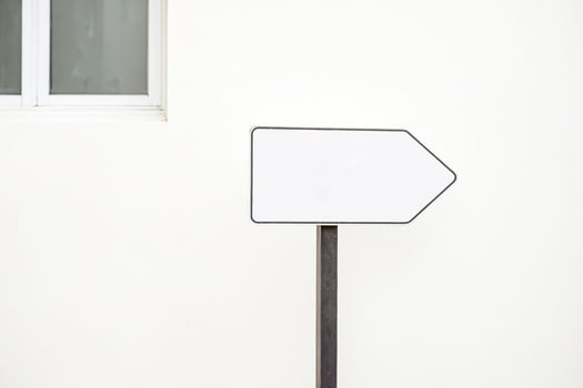 Blank White Arrow Sign on a White Wall photo