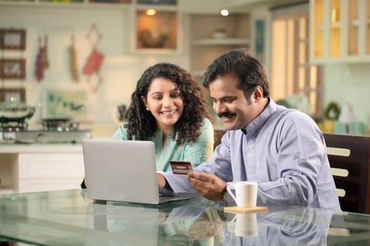 Husband And Wife Shopping Online And Paying With Credit Card At Laptop photo