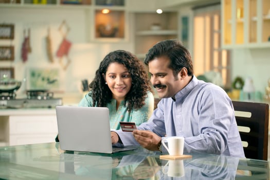 Happy Couple Using Credit Card While Shopping Online Through Laptop At Home photo