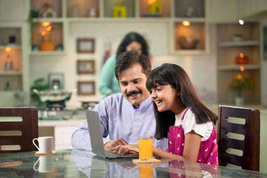 Handsome Father Looking At Daughter Working On Laptop photo