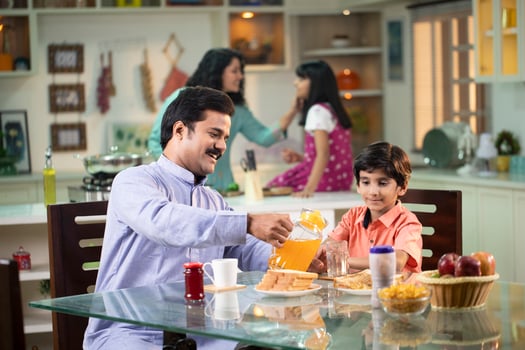 Mustache Dad Pouring Juice For Son At Table In Kitchen photo