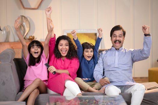 Family Sitting And Watching Cricket Match On Tv In Living Room photo
