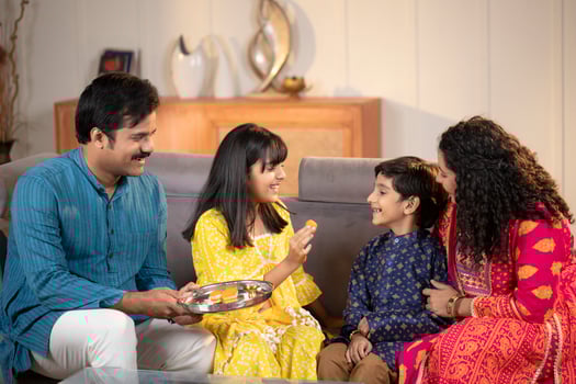 Beautiful Girl In Yellow Dress Feeding Laddu To Her Little Brother photo