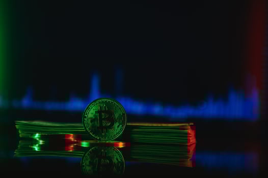 Golden bitcoin are stacked on a bright background of business graphs close-up. Bitcoin cryptocurrency. Folded in a tube 100 dollar bills photo
