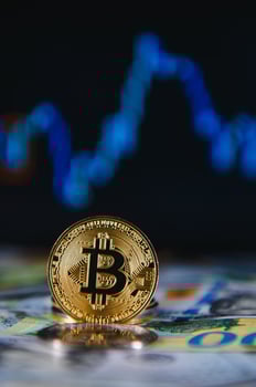 Close up heap of golden bitcoin physical coins on top of Euro, dollar banknotes background, high angle view, selective focus photo