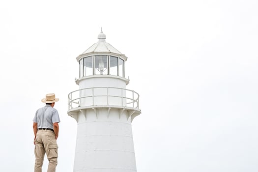 Man Standing By White Lighthouse photo