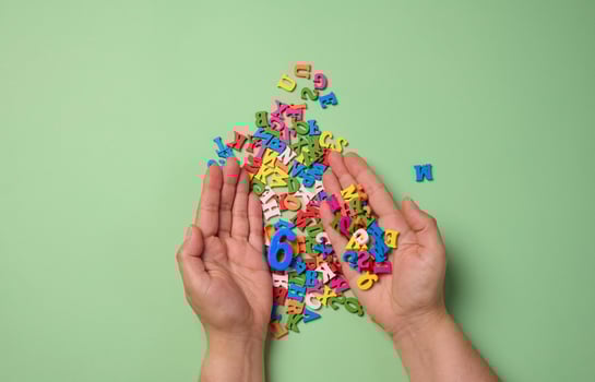 Two female hands and scattered wooden letters of the English alphabet on a green background photo