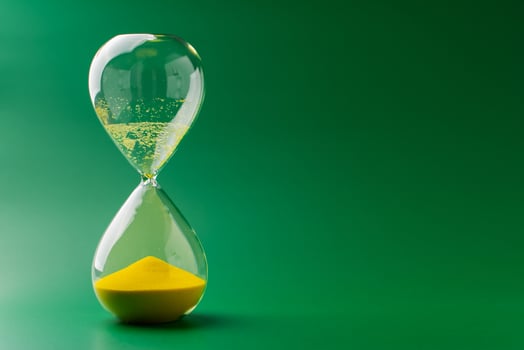 Hourglass standing still, working with time limit and limits, photo in studio on green background