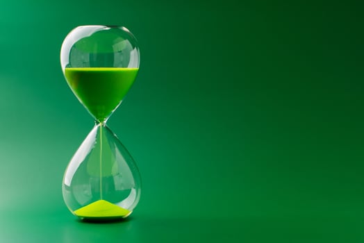 Hourglass standing still, working with time limit and limits, photo in studio on green background