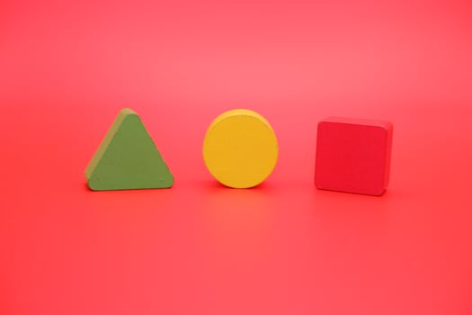 colorful wooden toys isolated red background. wooden toys shaped like triangles, squares and circles. photo
