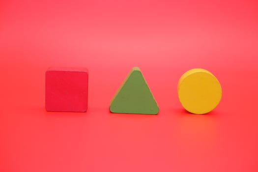colorful wooden toys isolated red background. wooden toys shaped like triangles, squares and circles. photo