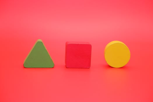 colorful wooden toys isolated red background. wooden toys shaped like triangles, squares and circles. photo