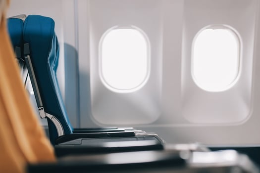 Side view millennial businessman drinking coffee, and using laptop while sitting comfortable seat on airplane cabin photo