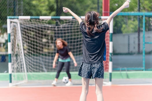 Mom with a child playing football in the urban outdoor futsal court photo