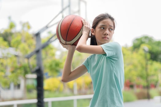 Active Asian kid girl playing basketball in the urban outdoor basketball court, Healthy life concepts photo