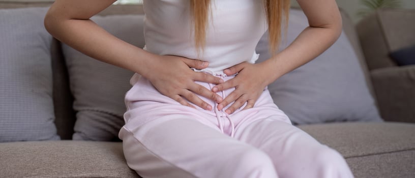 Young woman suffering from stomach ache on sofa at home photo