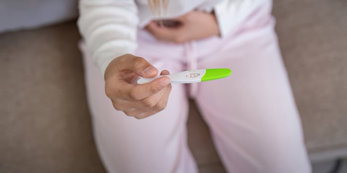 Positive pregnancy test held by woman at home, showing happiness. Concept of new beginnings and joyful discovery photo