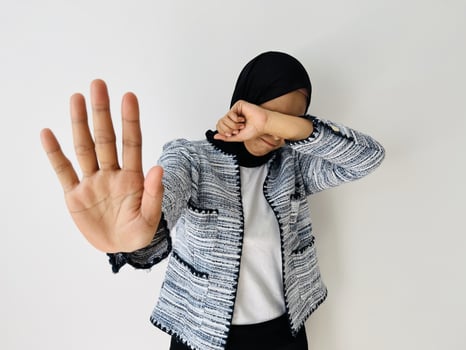 A young Muslim Asian woman feed sad hiding face with hand and putting other hand up to stop, gesture refusing isolated by white background photo