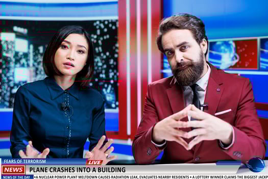 Presenters reveal terrorism danger as plane crashes into tall building, causing fear and madness among citizens. Newscasters team address airplane terrorist attack, worrying breaking news. photo