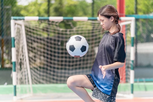 Asian child girl playing football in the urban outdoor futsal court photo