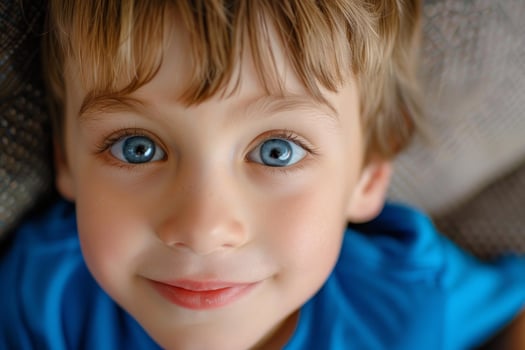 Portrait of a smiling young boy with big blue eyes lying down photo