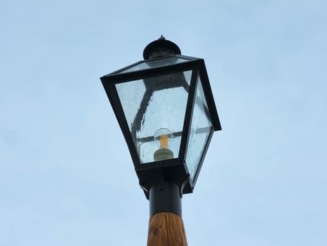 Antique lantern with an electric light bulb against a gloomy sky. photo