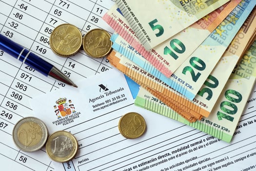KYIV, UKRAINE - APRIL 20, 2024 Agencia Tributaria logo from blank tax form and many euro banknotes on office table photo