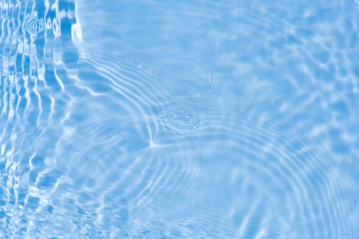 Bluewater waves on the surface ripples blurred. Defocus blurred transparent blue colored clear calm water surface texture with splash and bubbles. Water waves with shining pattern texture background. photo