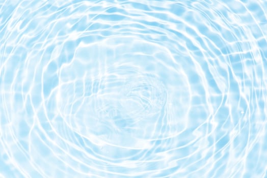 Bluewater waves on the surface ripples blurred. Defocus blurred transparent blue colored clear calm water surface texture with splash and bubbles. Water waves with shining pattern texture background. photo