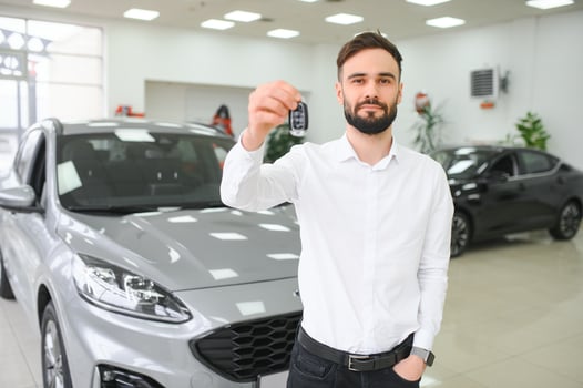 Happy young guy checking new luxury car, buying automobile at dealership centre. Portrait of cheerful millennial Caucasian man examining auto at showroom store photo