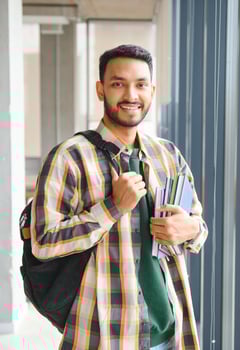 Handsome young Indian boy student with books and backpack at university. Education concept photo