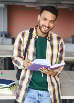 Handsome young Indian boy student with books and backpack at university. Education concept photo