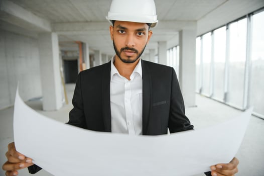Asian engineer handsome man or architect with white safety helmet in construction site. Standing at modern building construction. Worker asian man working project building photo
