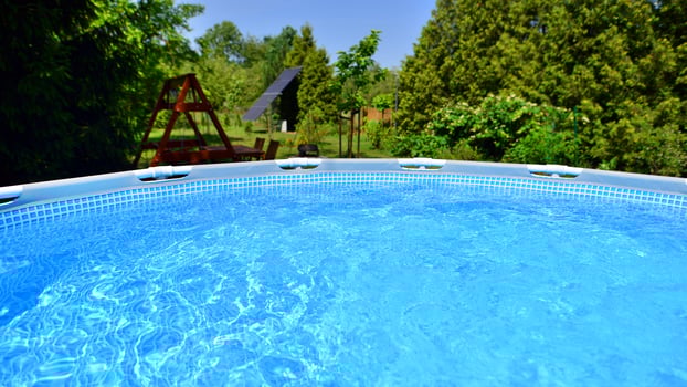 Swimming pool with metal frame for home and garden. Frame swimming pool in the yard. Garden in the background. Summer holiday fun and recreation. photo
